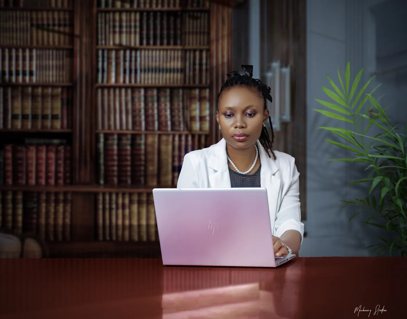 Dina Yerima-Avazi writing at her laptop in a book-lined study